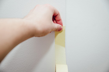 Poster - The man glues a security tape to the wall. A special protective tape protects the wall against painting, accuracy during renovation works at home.