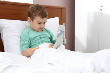 Wall Mural - Little child with intravenous drip and toy in hospital bed