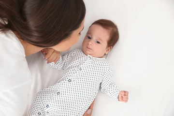 Wall Mural - Happy woman with her baby on bed, above view