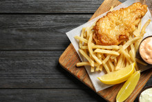 Board With British Traditional Fish And Potato Chips On Wooden Background, Top View. Space For Text
