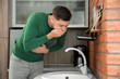 © New Africa - Young man having nausea in kitchen. Feeling sick