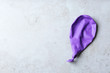 Purple deflated balloon on grey background, top view with space for text
