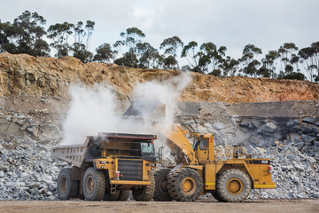 Wall Mural - Dumper truck being filled by a bulldozer at a stone quarry in Victoria, Australia
