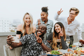 Diverse group of friends taking a selfie at a rooftop party