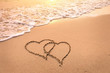 © NicoElNino - Romantic honeymoon holiday or Valentine's day on the beach concept with two hearts drawn on the sand, tropical getaway for couples, love symbol