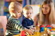 © Oksana Kuzmina - Nursery babies kids playing with teacher in kindergarten
