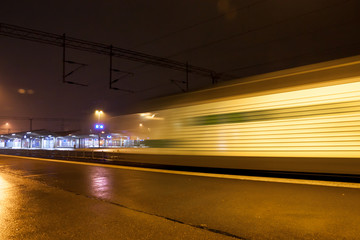 Wall Mural - Train in motion on the station at night, long exposure photo.