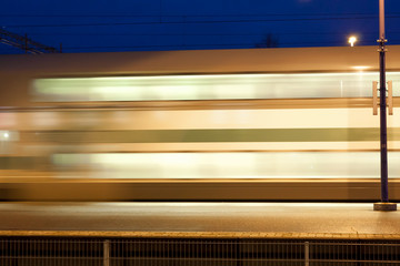 Wall Mural - Train in motion on the station at night, long exposure photo.