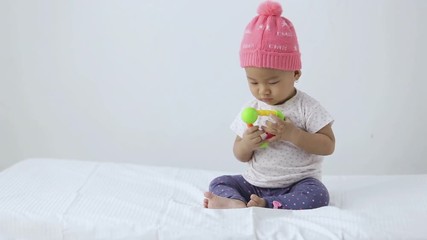 Wall Mural - happy little baby girl put a toy in her mouth while sitting