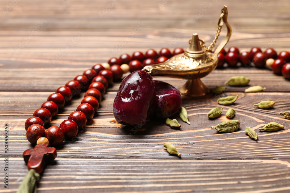 Aladdin lamp, tasbih and dates on wooden table