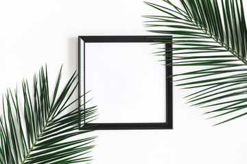 Summer composition. Tropical palm leaves, black photo frame on white background. Summer, nature concept. Flat lay, top view, copy space