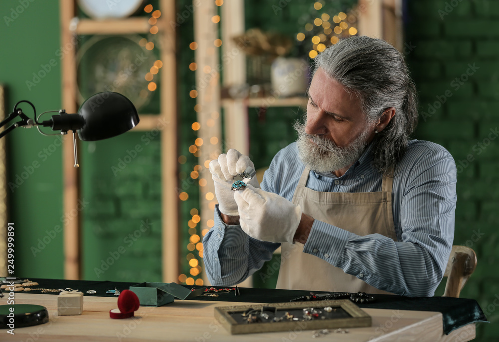 Jeweller examining adornment in workshop