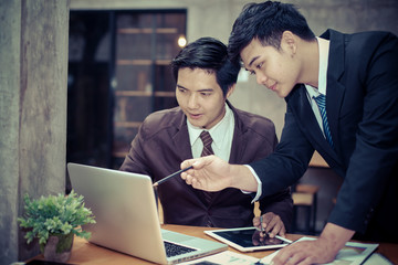 Image of two young asia businessmen using touchpad at meeting