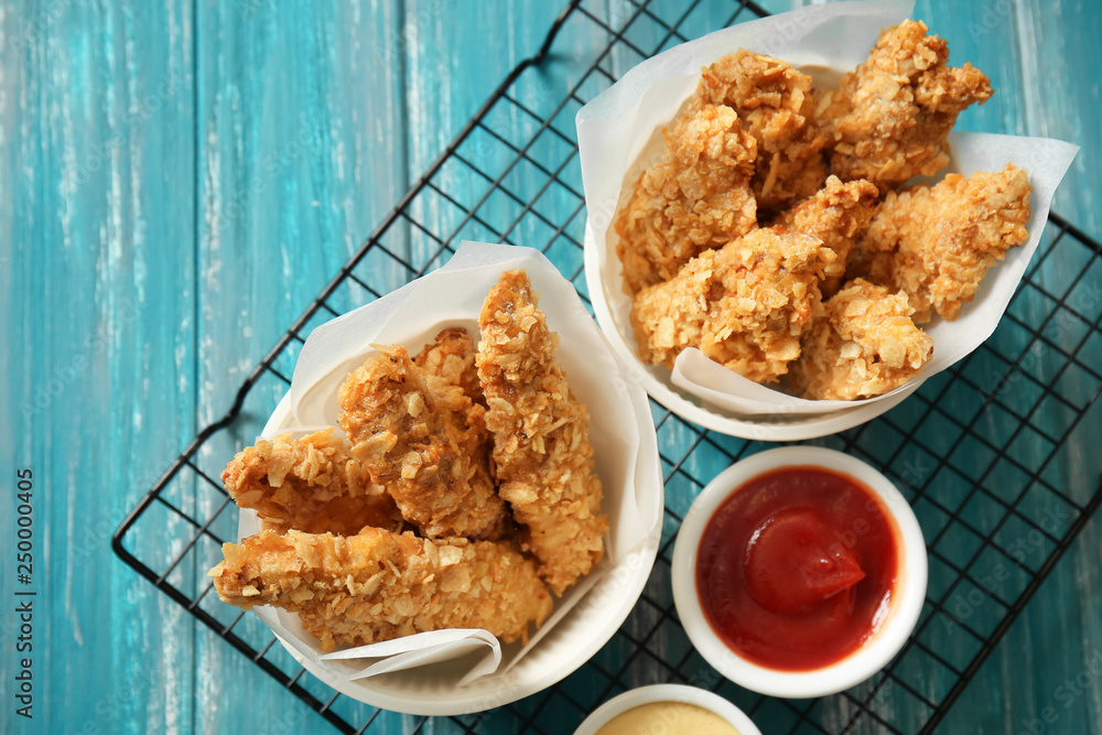 Cooling rack with tasty nuggets and sauces on table
