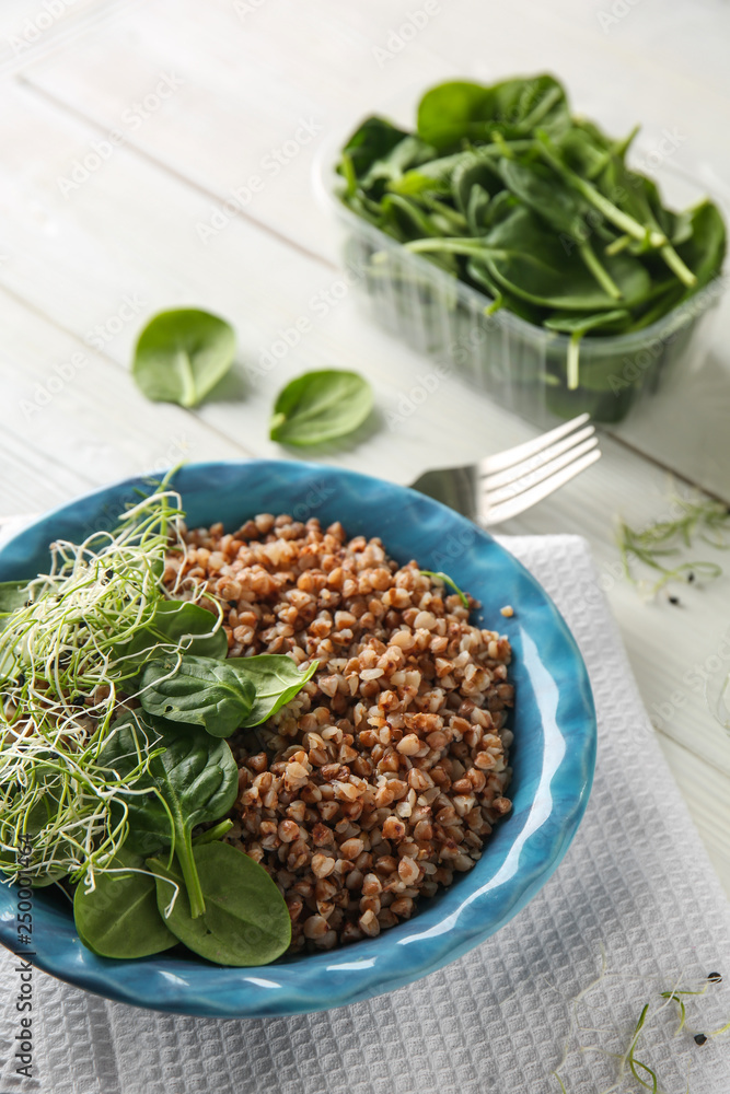 Bowl with tasty boiled buckwheat on white table