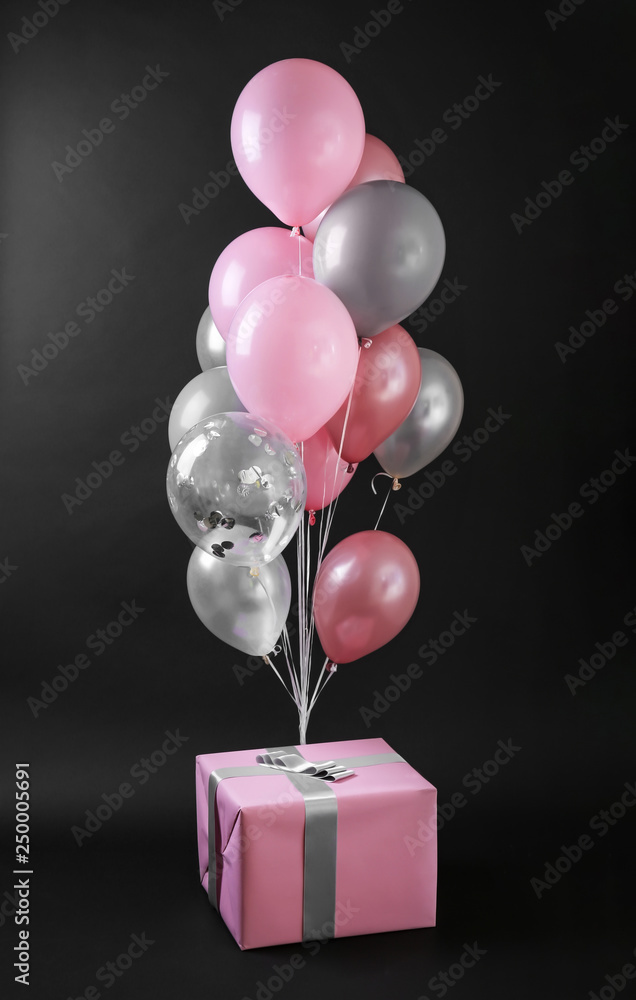Gift box and balloons on dark background
