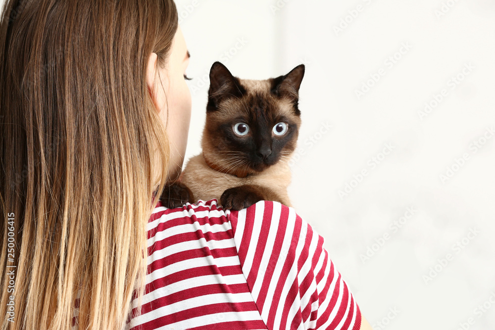 Young woman with cute funny Thai cat at home