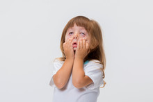 Close-up Portrait Of Little Girl's Face. Girl Grimacing, Covering Her Face With Her Hands