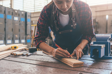 Wall Mural - Carpenter working with equipment on wooden table in carpentry shop. woman works in a carpentry shop.