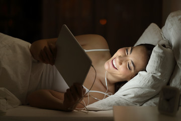 Sticker - Happy woman watching movie on a tablet in the night