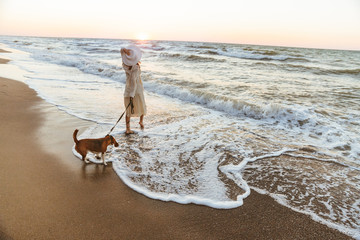 Sticker - Image of caucasian woman 20s in summer straw hat, walking by seaside with her dog