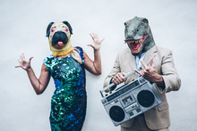 Crazy Senior Couple Dancing For Party Wearing T-rex And Chicken Mask - Old Trendy People Having Fun Listening Music With Boombox Stereo - Absurd And Funny Trend Concept - Focus On Dino Face