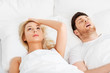 sleeping problems and people concept - unhappy woman lying in bed with snoring man