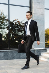 Handsome young businessman walking outdoors at the street.