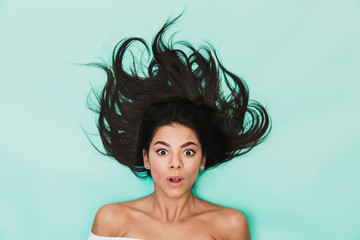 Wall Mural - Shocked young woman lies isolated on blue light background. Healthy hair concept.