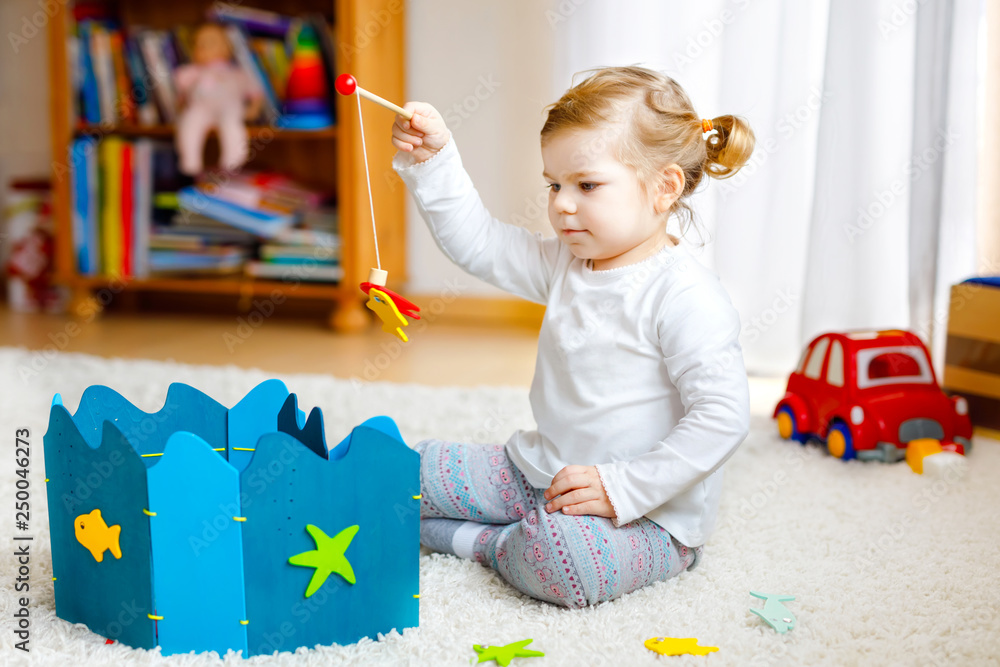 Adorable cute toddler girl playing with wooden fishing game at home or ...