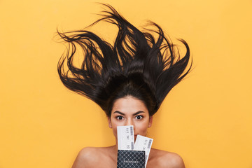 Poster - Young woman lies isolated on yellow background holding passport with tickets.