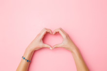 Heart Shape Created From Young Woman's Hands On Pastel Pink Background. Love And Happiness Concept. Empty Place For Emotional, Sentimental Text, Quote Or Sayings. Closeup. Top View.