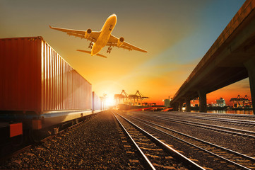 Wall Mural - cargo plane flying over container trains and commercial shipyard background