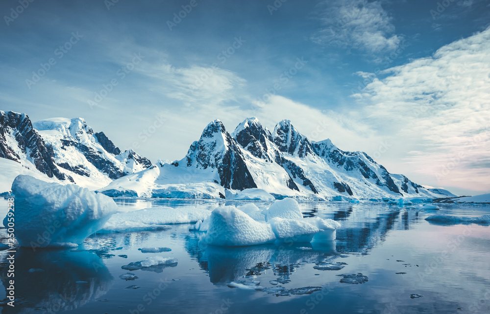 Blue Ice covered mountains in south polar ocean. Winter Antarctic landscape. The mount's reflection in the crystal clear water. The cloudy sky over the massive rock glacier. Travel wild nature - obrazy, fototapety, plakaty 