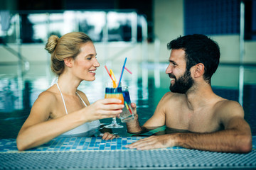 Wall Mural - Happy attractive couple relaxing in swimming pool