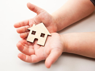 Wall Mural - A little child holds wooden flat house in his hands on the white background