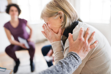 Wall Mural - A senior depressed woman crying during group therapy.