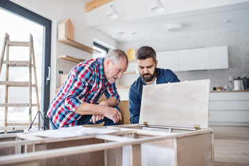 Wall Mural - A mature man with his senior father assembling furniture, a new home concept.