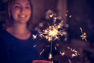 Happy girl is holding a sparkler at Christmas time