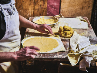 A cook making Tortillas on a wooden rustic table.