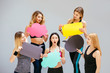 © Iryna - Group of five slim fitness women in sportswear holding varicoloured paper clouds indoor over grey wall background. Cope space text, diet, think, emotions, lose weight, choice and fitness concept.