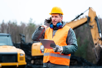 Porträt eines Arbeiters im Tagebau vor einem Bagger