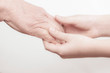 © leksann - the hands of an old man and a child holding each other on a white background. contrast. idea