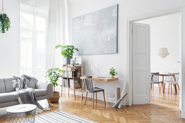 stylish scandinavian open space with design furniture, plants, bamboo bookstand and wooden desk. bro