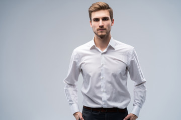 Portrait of handsome man in suit standing against gray background