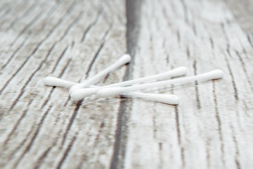 Sticker - Sticks on a wooden background. White ear buds with cotton wool lie on a brown, wooden background. The concept of cleaning the ears, the ear pinna.