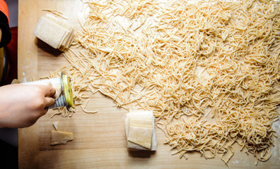 Canvas Print - Preparation of pasta by a child. The little boy helps mum to prepare the pasta. The boy uses a pasta machine to make pasta from the dough.