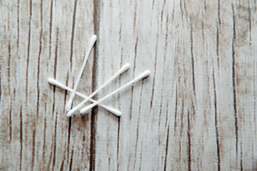 Sticker - Sticks on a wooden background. White ear buds with cotton wool lie on a brown, wooden background. The concept of cleaning the ears, the ear pinna.