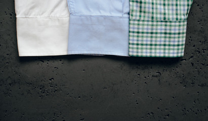 Poster - Cuffs from business shirts on a dark background. Vertical sleeves from shirts in green, blue and white. The concept of fashion and sale of luxury clothes.