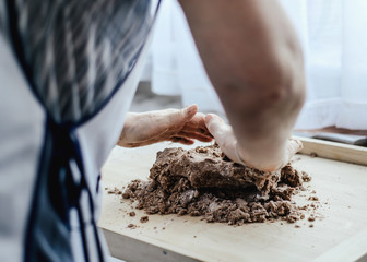 Canvas Print - Crushing the dough. Preparing the dough by a woman. A woman kneading dough and baking cookies and gingerbreads. Grandma, my mother prepares a delicious cake for the family. Family atmosphere.